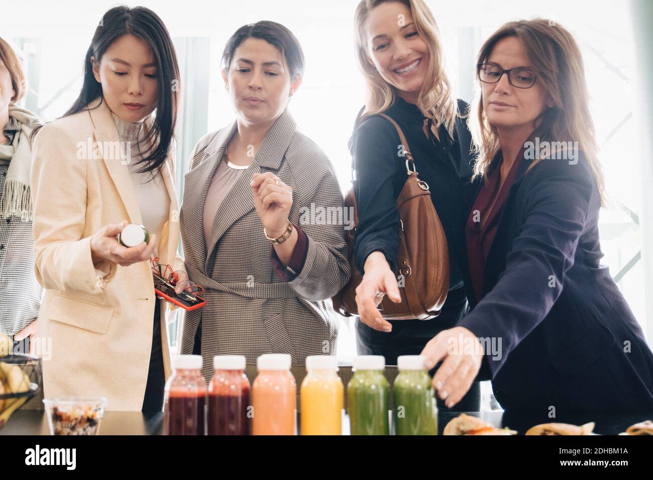 Multiethnische Geschäftsfrauen, die Essen und Trinken auf dem Tisch betrachten Ereignis Stockfoto