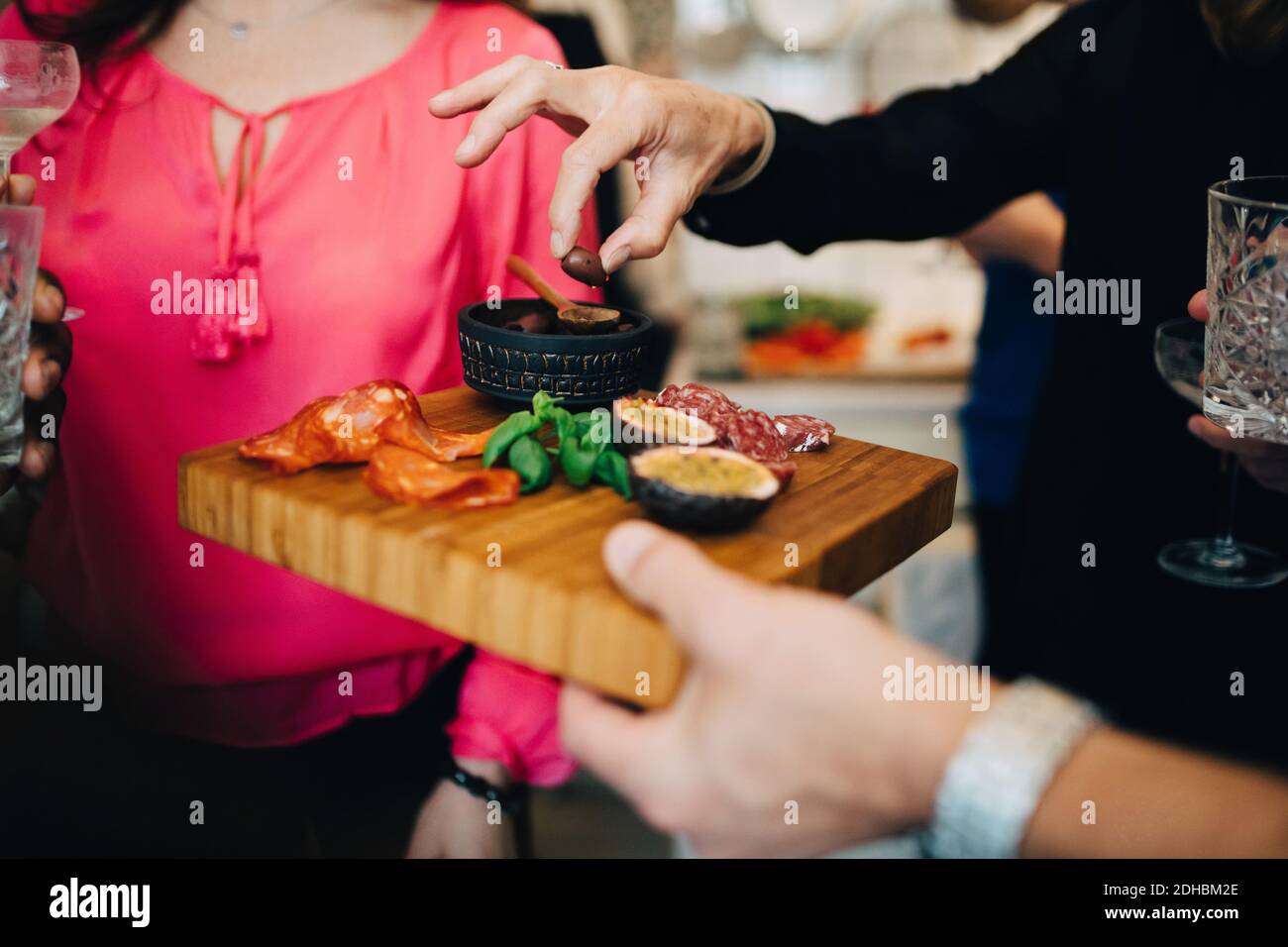 Kurze Hand des Mannes, der Essen an Freunde in der Party serviert Zu Hause Stockfoto