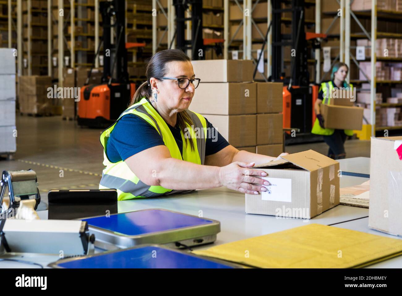 Reife weibliche Arbeiterin hält Pappkarton am Schreibtisch im Vertrieb Lager Stockfoto