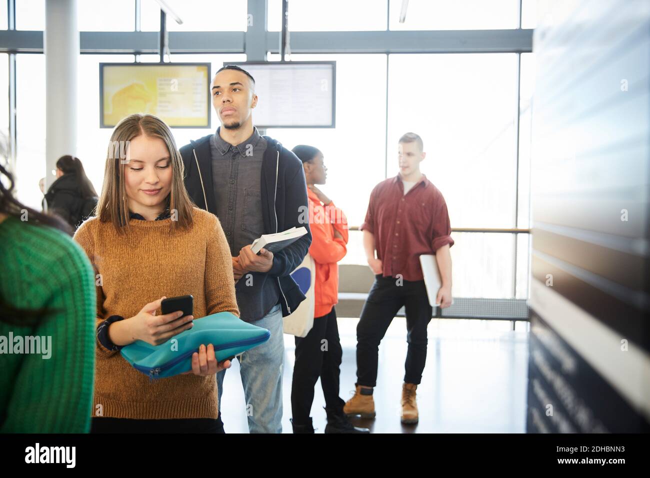 Junge Studenten und Studentinnen, die an der Universität in Reihe stehen Lobby Stockfoto