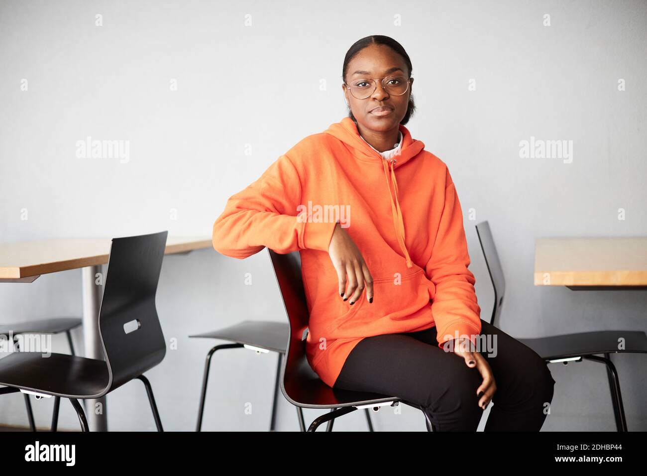 Portrait eines jungen Studenten auf dem Stuhl gegen die Wand sitzen universität Stockfoto