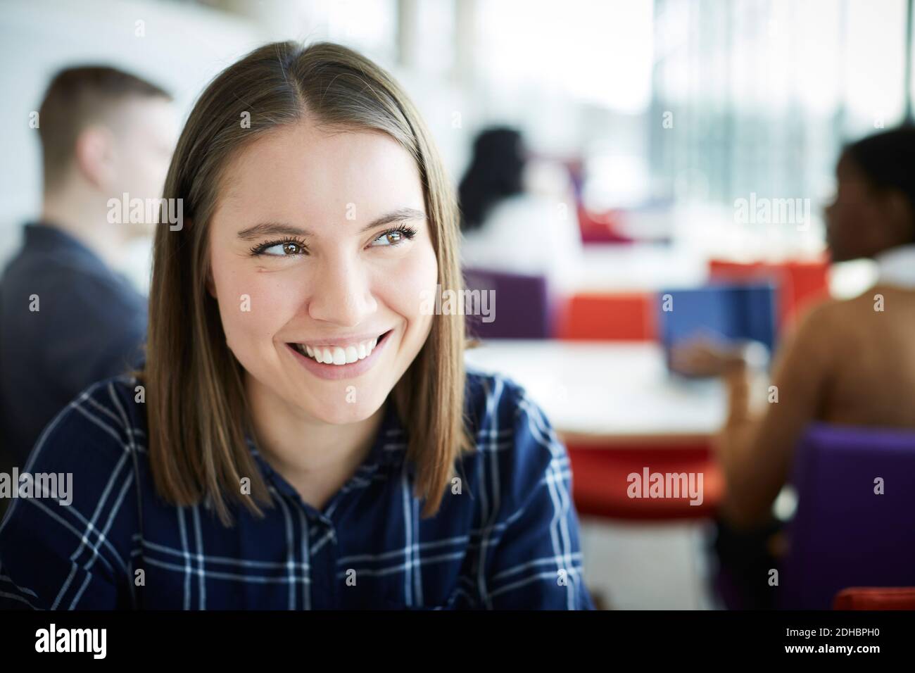 Nahaufnahme einer lächelnden Frau, die auf der Universität wegschaut Cafeteria Stockfoto