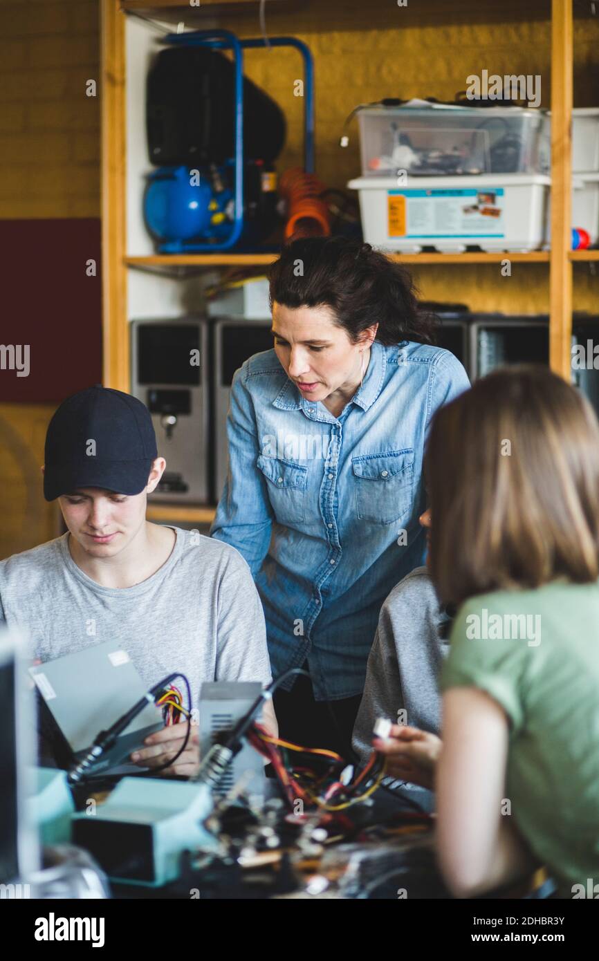 Reife Frau Lehrer Blick auf männliche High School Student Vorbereitung Wissenschaftliches Projekt im Klassenzimmer Stockfoto