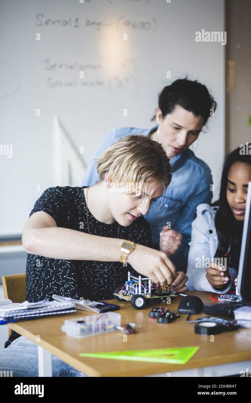 Reife weibliche Lehrer Blick auf Schüler Vorbereitung Spielzeug Auto auf Schreibtisch im Klassenzimmer Stockfoto