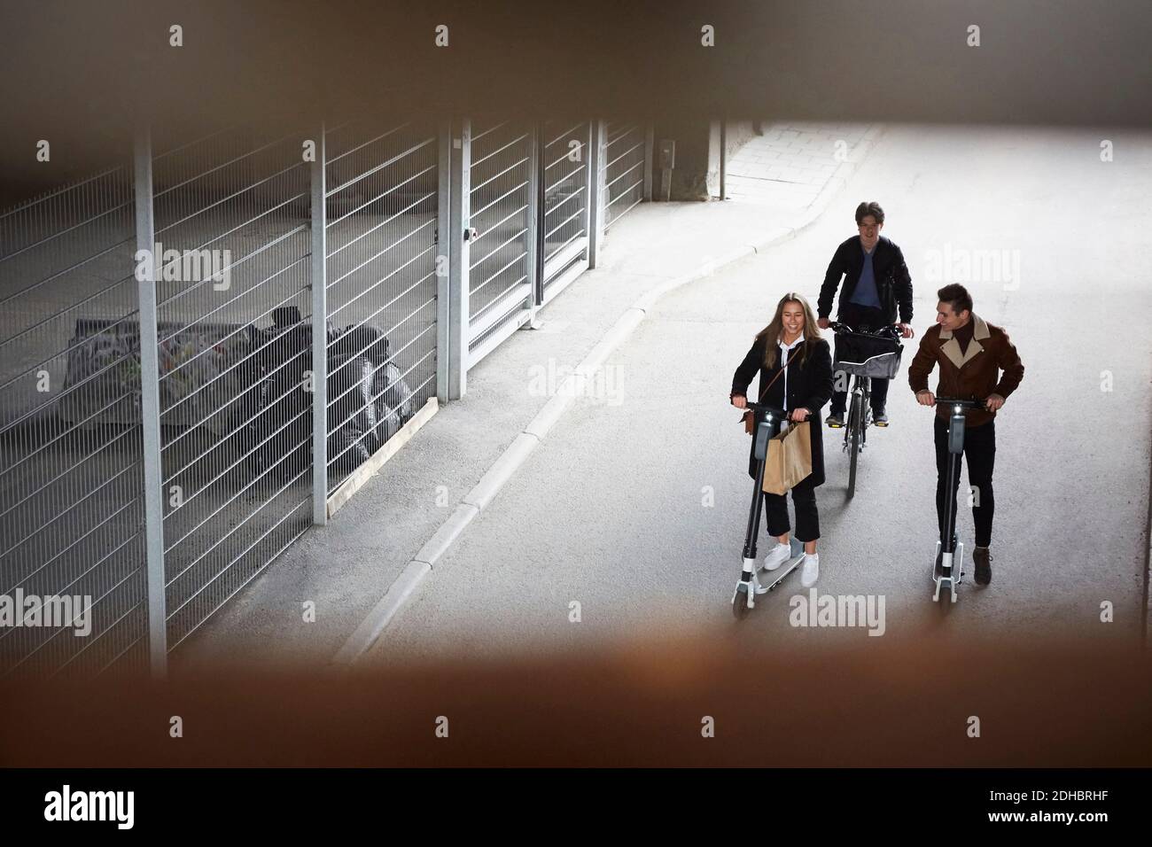 High-Angle-Ansicht der männlichen und weiblichen Teenager-Freunde Reiten Elektro-Roller und Fahrrad auf der Straße in der Stadt Stockfoto