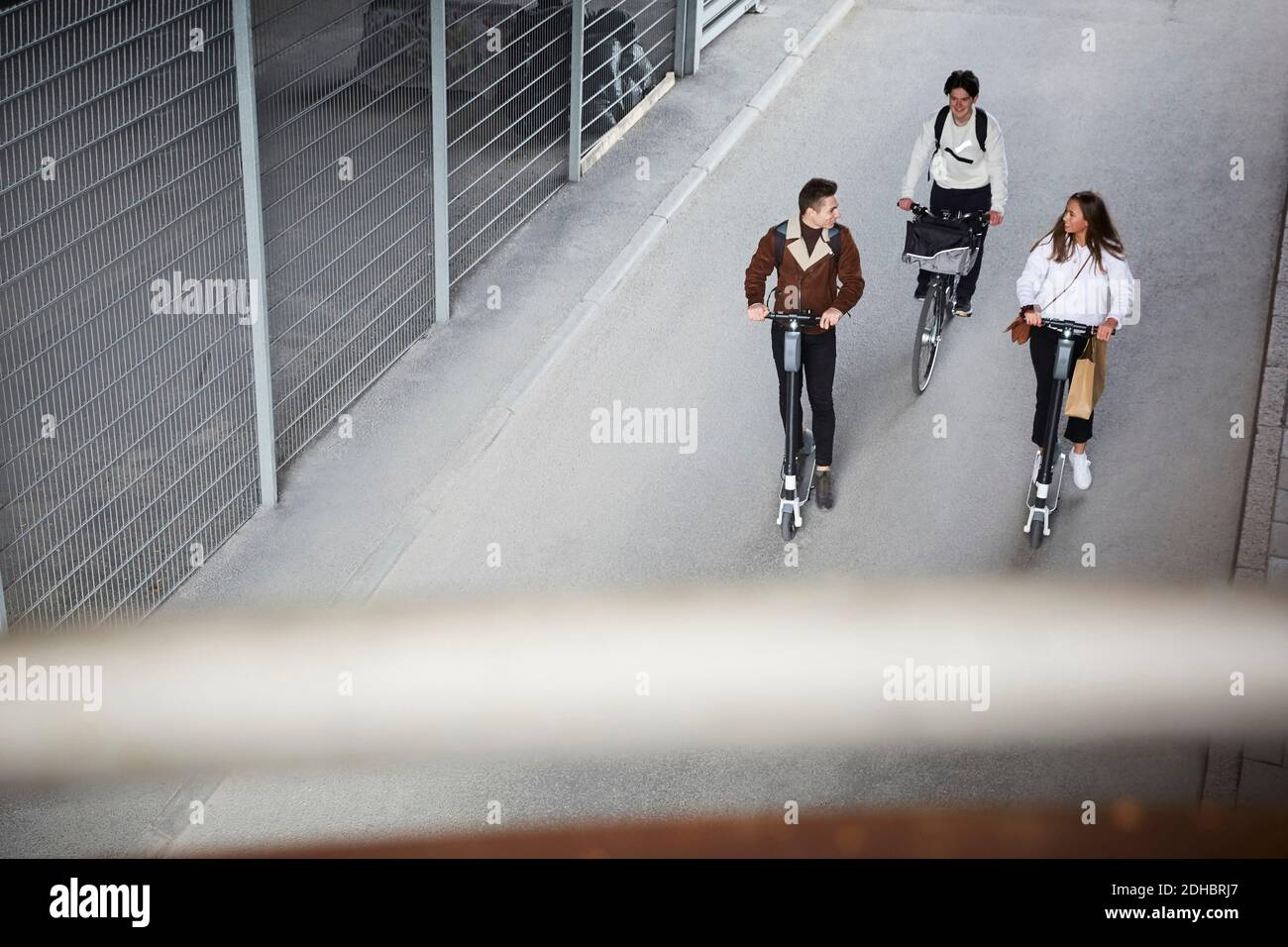 High-Angle-Ansicht der Teenager-Freunde Reiten Elektro-Push-Scooter Und Fahrrad auf der Straße in der Stadt Stockfoto