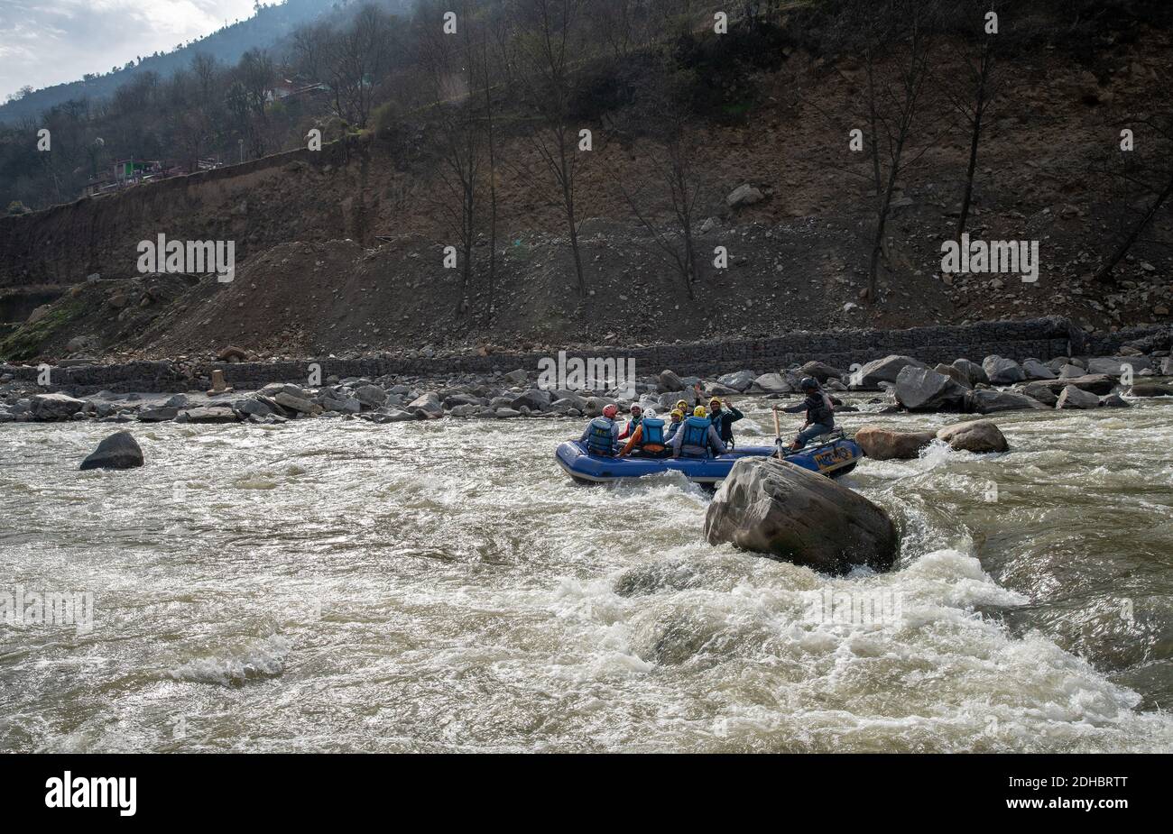 02-10-2019 Kullu, Indien. Fröhliche Menschen - Passagiere auf Gummiboot Lenkung - Rafting auf dem Fluss Beas mit großen Steinen Stockfoto