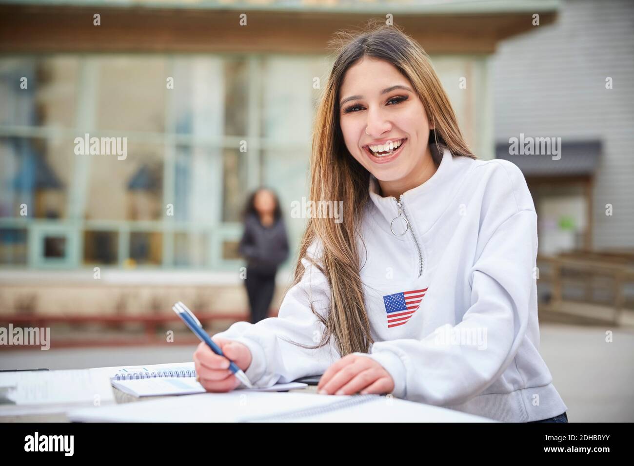 Porträt eines lächelnden Teenagers, das am Tisch auf dem Schulhof sitzt Stockfoto