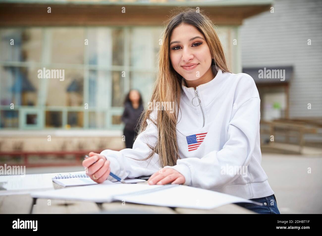 Portrait von selbstbewussten Teenager-Mädchen am Tisch im Schulhof sitzen Stockfoto