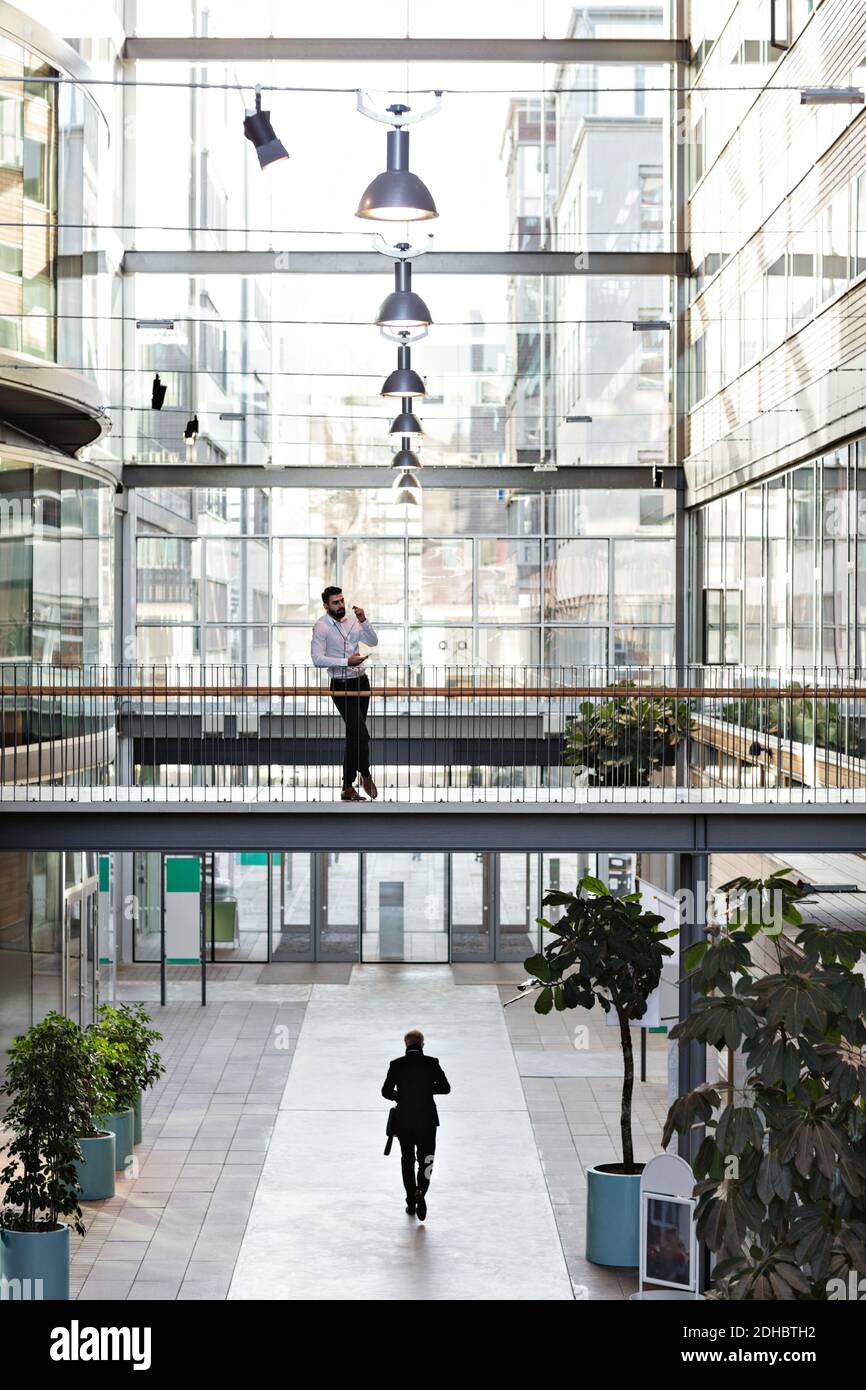 Junger Geschäftsmann steht in der Lobby im Atrium des Büros Stockfoto