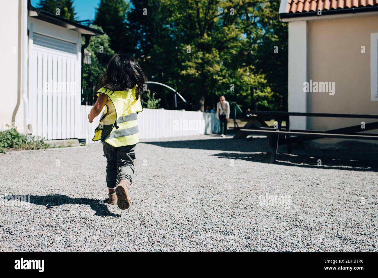 Volle Länge Rückansicht Mädchen läuft außerhalb Vorschule Gebäude auf Sonniger Tag Stockfoto