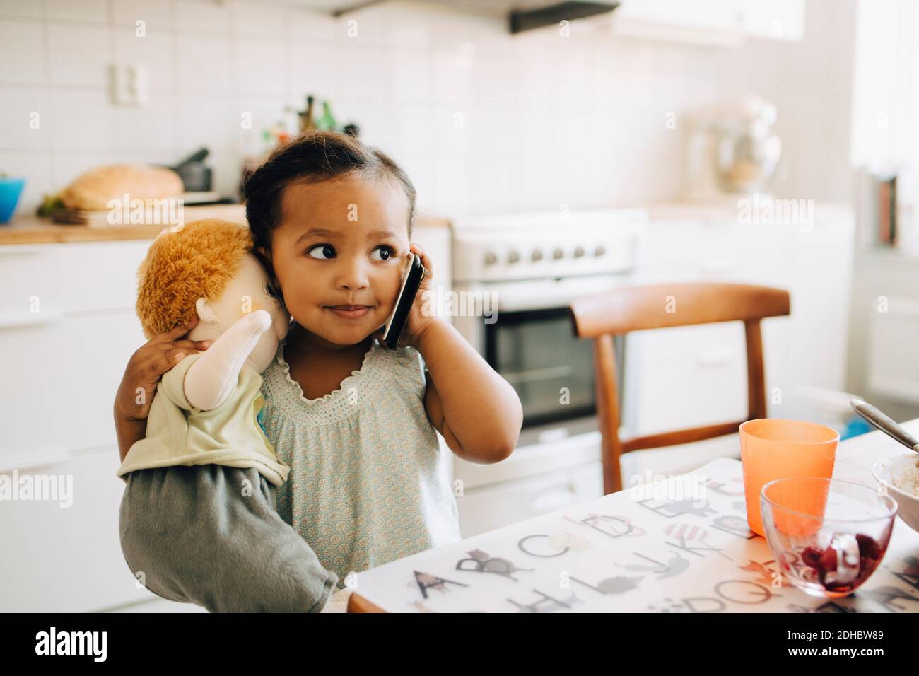 Mädchen, die auf dem Smartphone reden, während sie am Tisch stehen Esszimmer Stockfoto