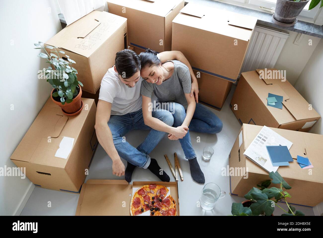 Blick aus dem hohen Winkel auf ein Paar, das sich beim Pizza-Essen ausruhte Bei Umzug des neuen Hauses Stockfoto