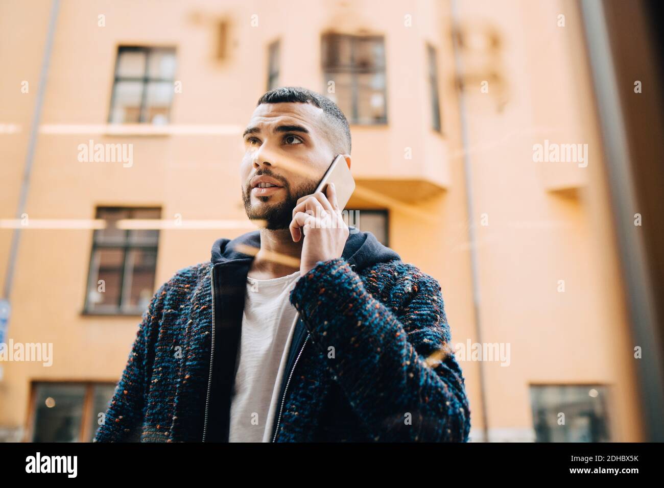 Low-Winkel-Ansicht des selbstbewussten jungen Geschäftsmann im Gespräch auf smart Telefon durch Fenster gesehen Stockfoto