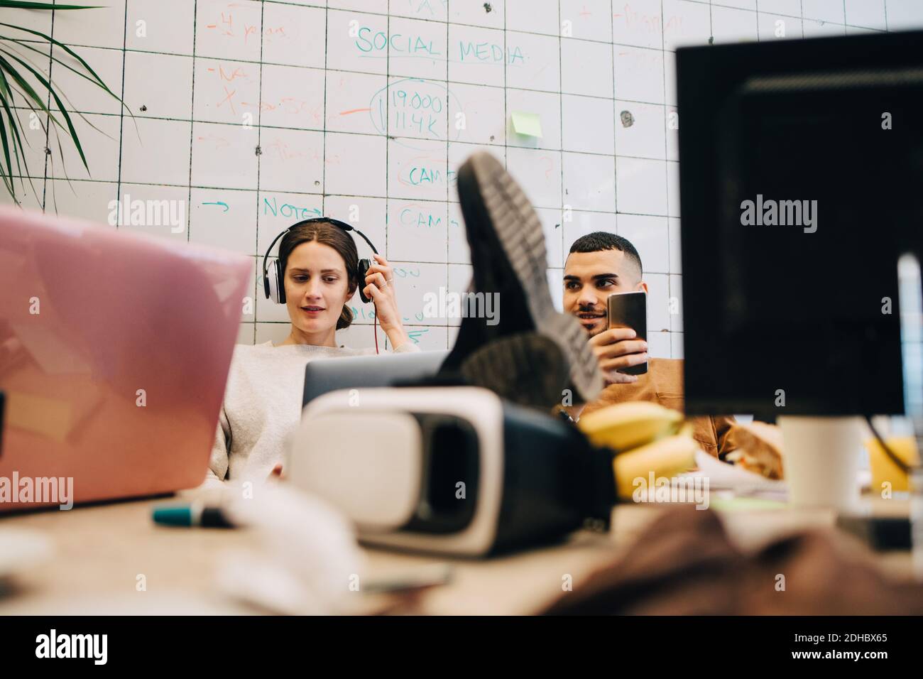 Junge Geschäftskollegen sitzen im Kreativbüro an der Fliesenwand Stockfoto