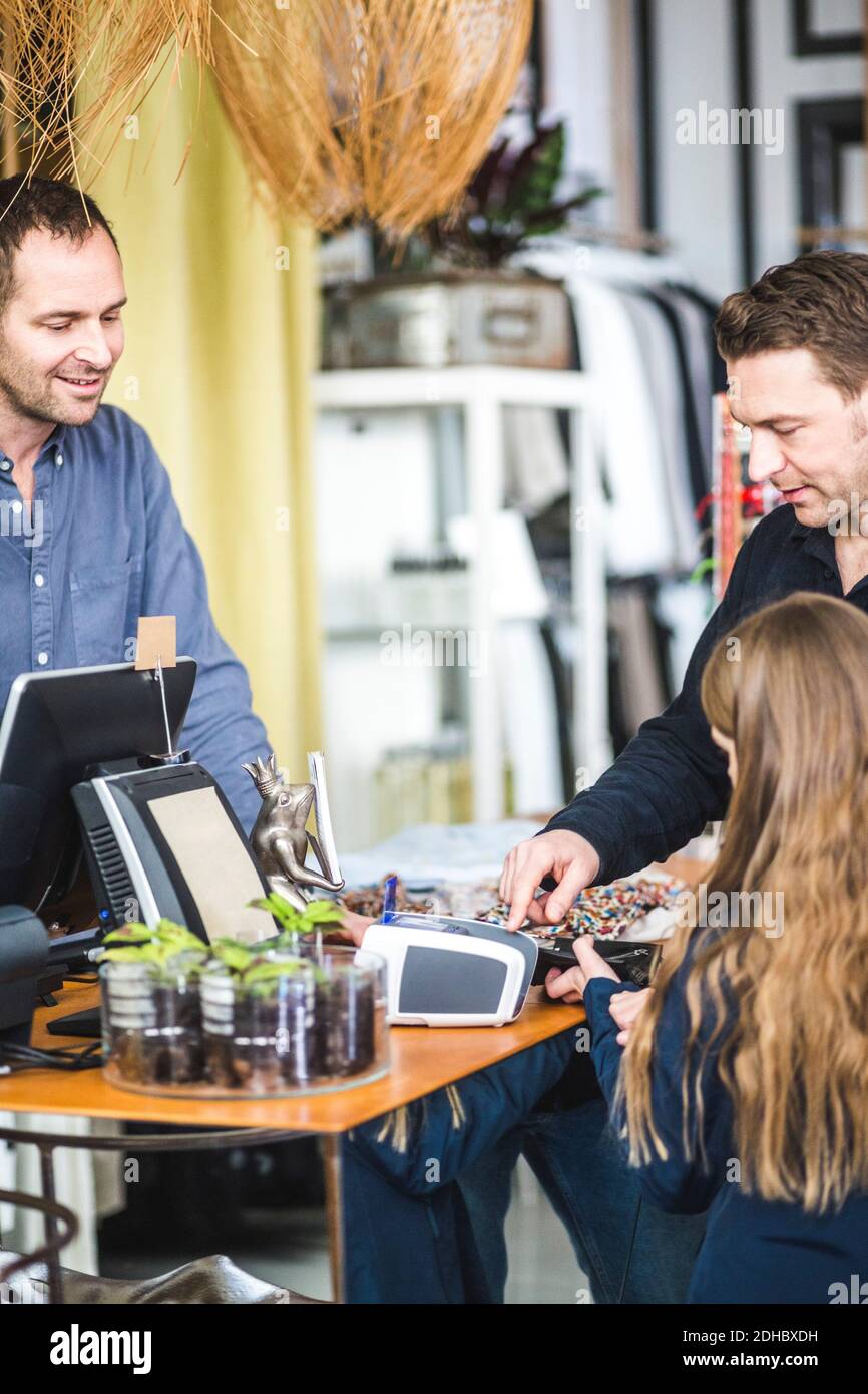 Mädchen tippt PIN-Code an der Kasse im Bekleidungsgeschäft Von Vater Stockfoto