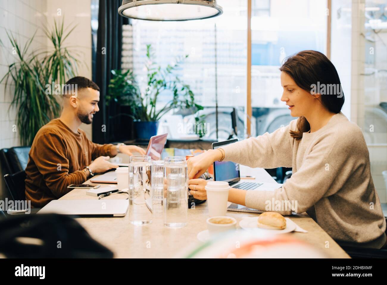 Seitenansicht der jungen multi-ethnischen männlichen und weiblichen Hacker arbeiten Am Schreibtisch im Kreativbüro Stockfoto