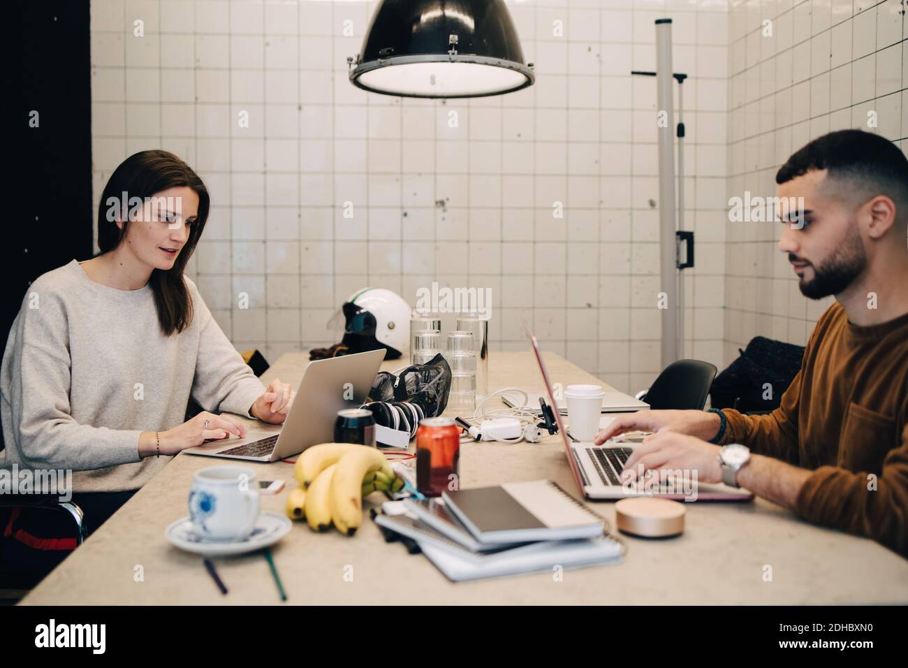 Junge männliche und weibliche Hacker mit Laptops für die Codierung an Schreibtisch in kleinen Büros Stockfoto