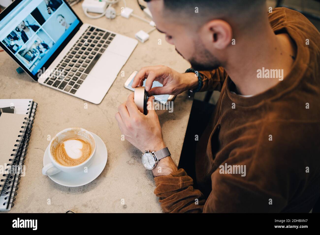 High-Angle-Ansicht der jungen Computer-Programmierer hält Ausrüstung durch Kaffee auf dem Schreibtisch in einem kleinen Kreativbüro Stockfoto