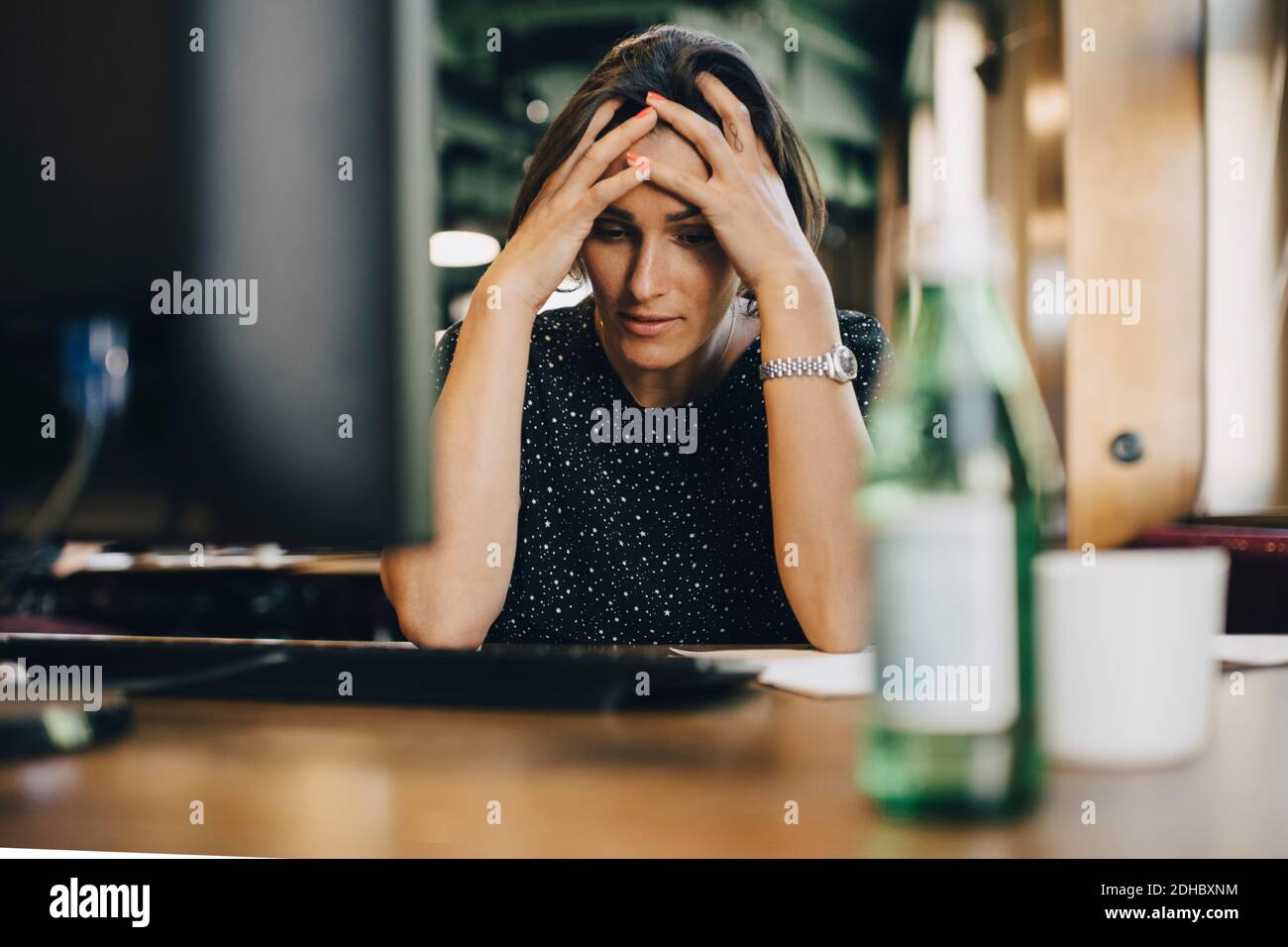 Frustrierte weibliche Computerprogrammiererin mit Kopf in den Händen im Büro Schreibtisch Stockfoto