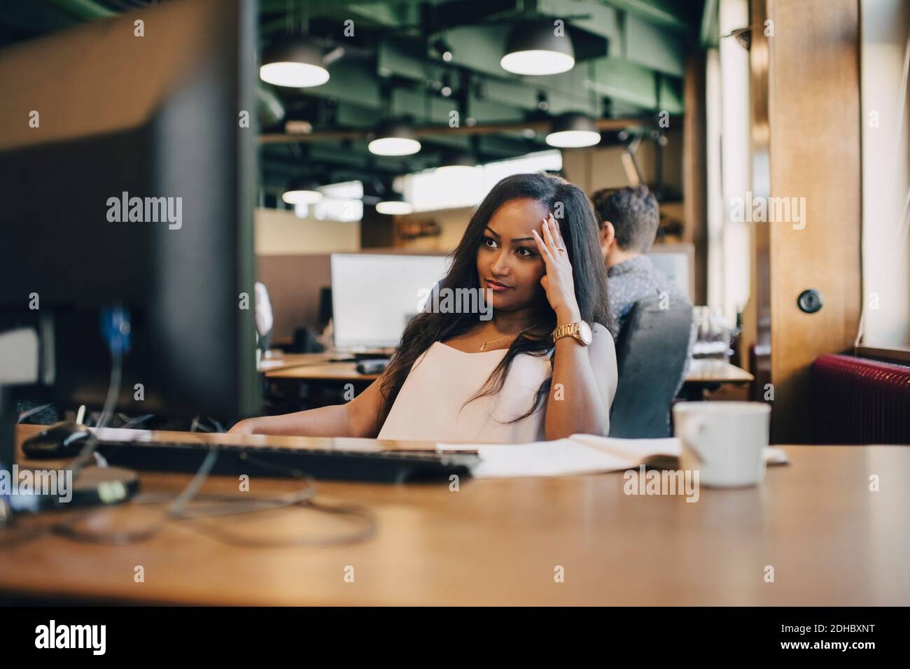 Konzentrierte Geschäftsfrau, die Computermonitor im Büro betrachtet Stockfoto