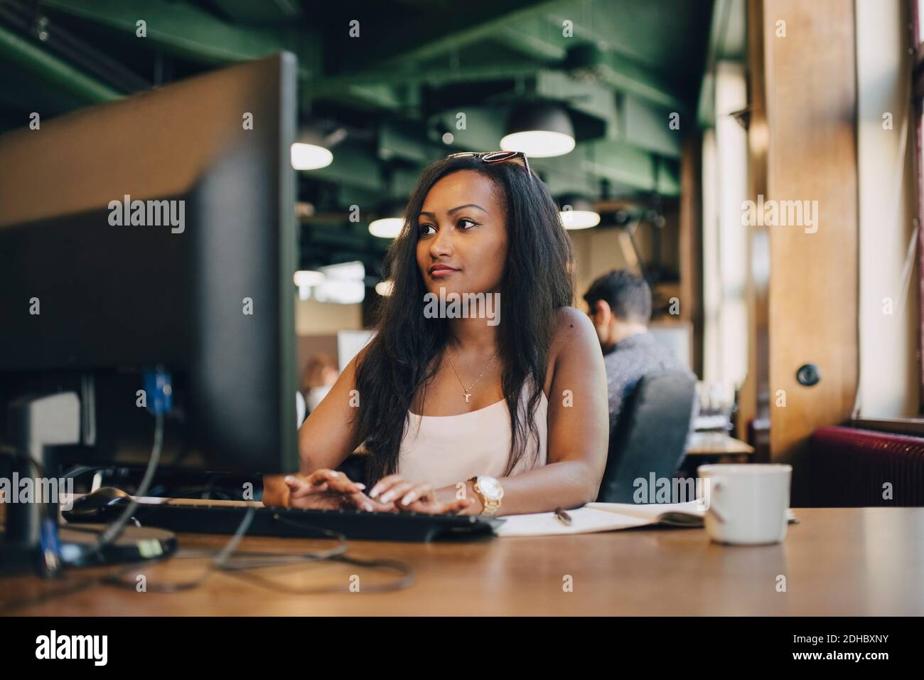 Junge Geschäftsfrau mit Computer am Schreibtisch im kreativen Büro Stockfoto