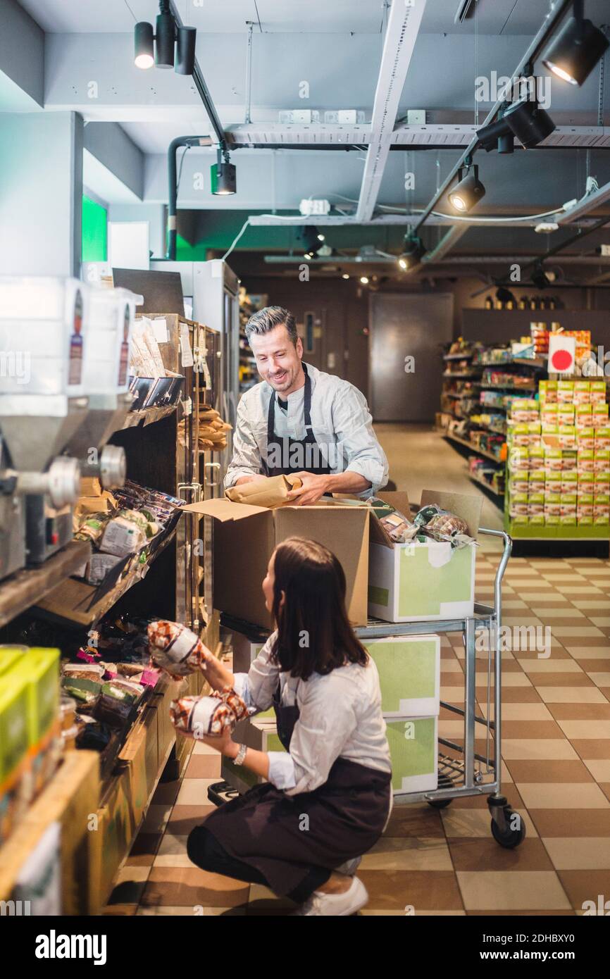 Unternehmer, die Pakete in den Regalen im Supermarkt arrangieren Stockfoto