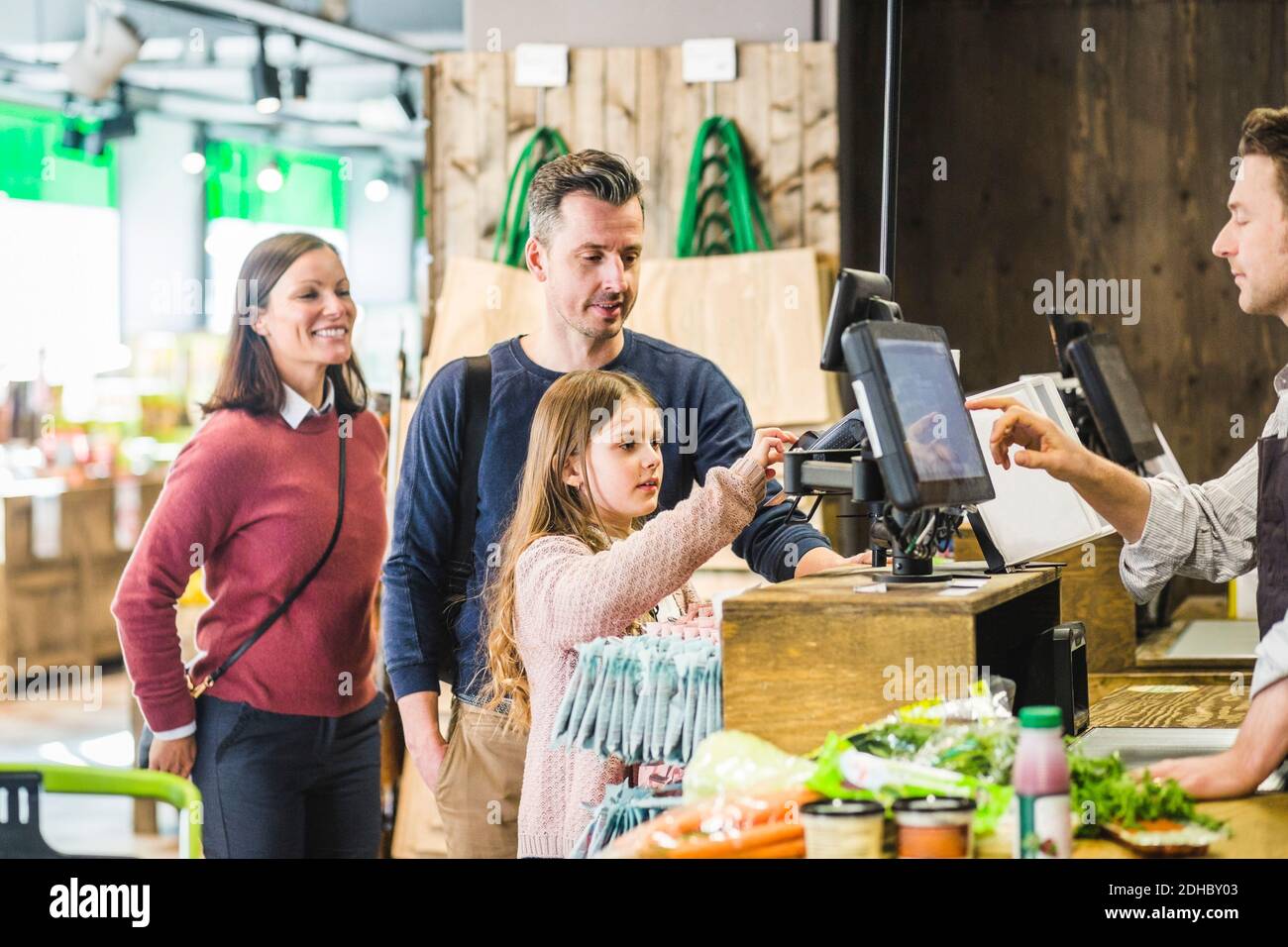 Nettes Mädchen Eingabe PIN-Code an der Kasse Schalter im Supermarkt Nach Familie Stockfoto