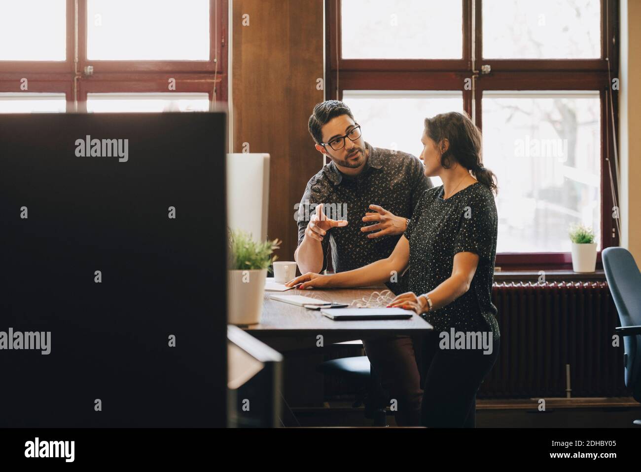 Mittelerwachsener Geschäftsmann diskutiert neuen Plan mit weiblichen Kollegen in Büro Stockfoto