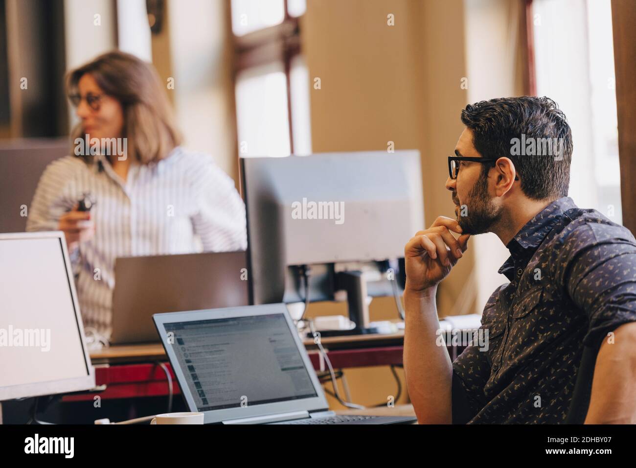 Mittelerwachsener Geschäftsmann, der eine Kollegin in einem neuen Büro ansieht Stockfoto