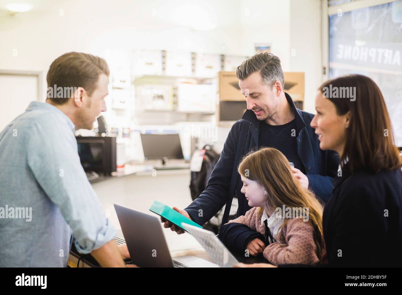 Reifer Mann, der Paket anschaut, während er mit Familie im Stehen ist Elektronikgeschäft Stockfoto