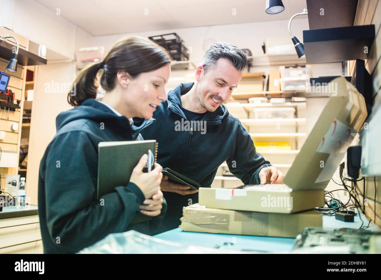 Lächelnde Computertechniker, die in der Werkstatt in einen Karton schauen Stockfoto