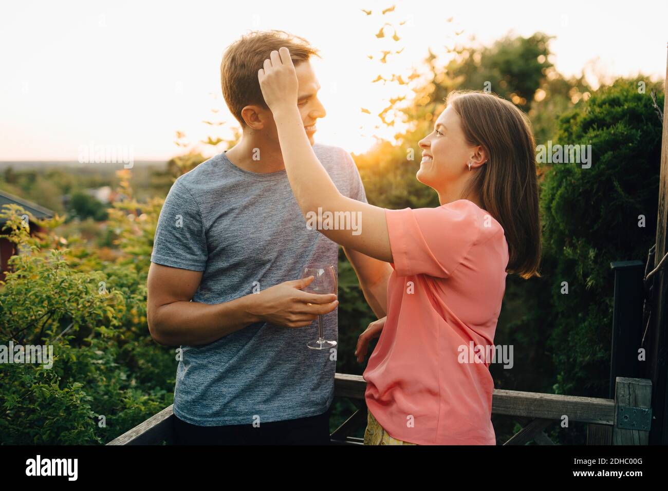 Lächelndes Paar, das sich unterhielt, während es auf dem Balkon im Hof stand Stockfoto