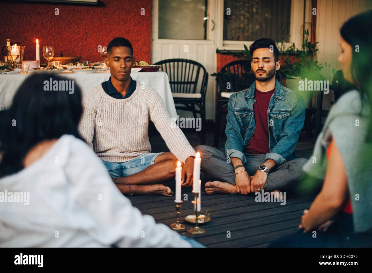 Multiethnische männliche und weibliche Freunde sitzen mit geschlossenen Augen Balkon während der Gruppensitzung Stockfoto