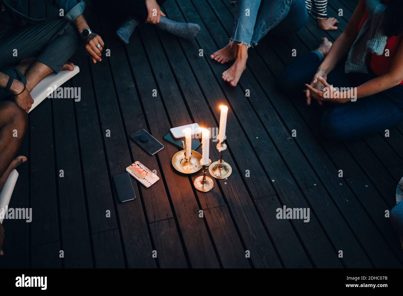 High-Winkel-Ansicht von Freunden sitzen um brennende Kerzen und Mobiltelefone auf dem Balkon während der Gruppentherapie Stockfoto