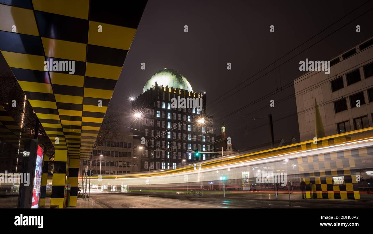 Hannover, Deutschland. Dezember 2020. Beleuchtete Fenster lassen im Rahmen eines Adventkalenders die Zahl 10 an der Fassade des Anzeiger-Hochhauses erstrahlen - abends fährt eine Straßenbahn am Denkmal vorbei (Aufnahme mit langer Belichtungszeit). Quelle: Moritz Frankenberg/dpa/Alamy Live News Stockfoto