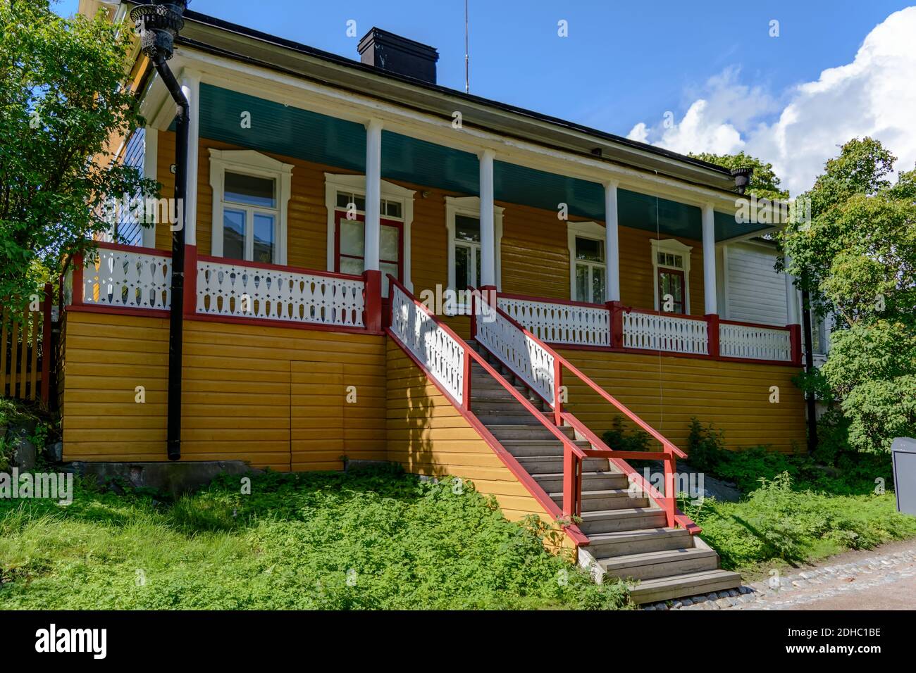 Gelbes Holzhaus im russischen Handelsblock in der Festung Suomenlinna, mit Säulenveranda, hohen Eingangstüren und Steinsockel, sowie dekorativ Stockfoto