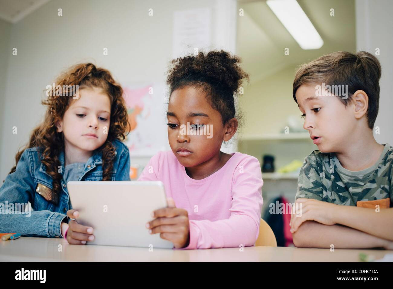 Schulfreunde lernen mit einem digitalen Tablet am Schreibtisch im Klassenzimmer Stockfoto