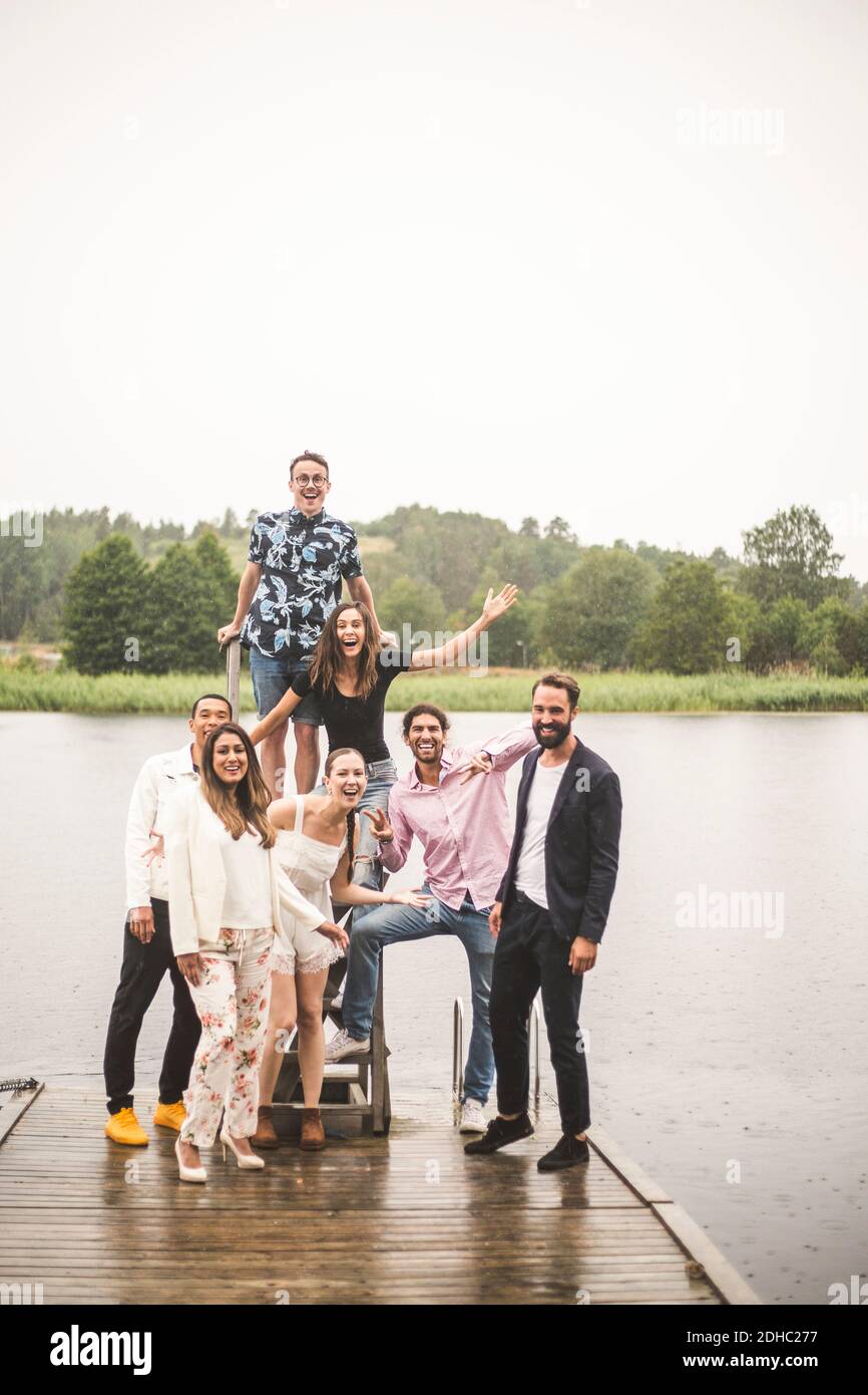 Portrait von fröhlichen, multi-ethischen Freunden, die auf dem Steg über dem See stehen Während der Ferien Stockfoto