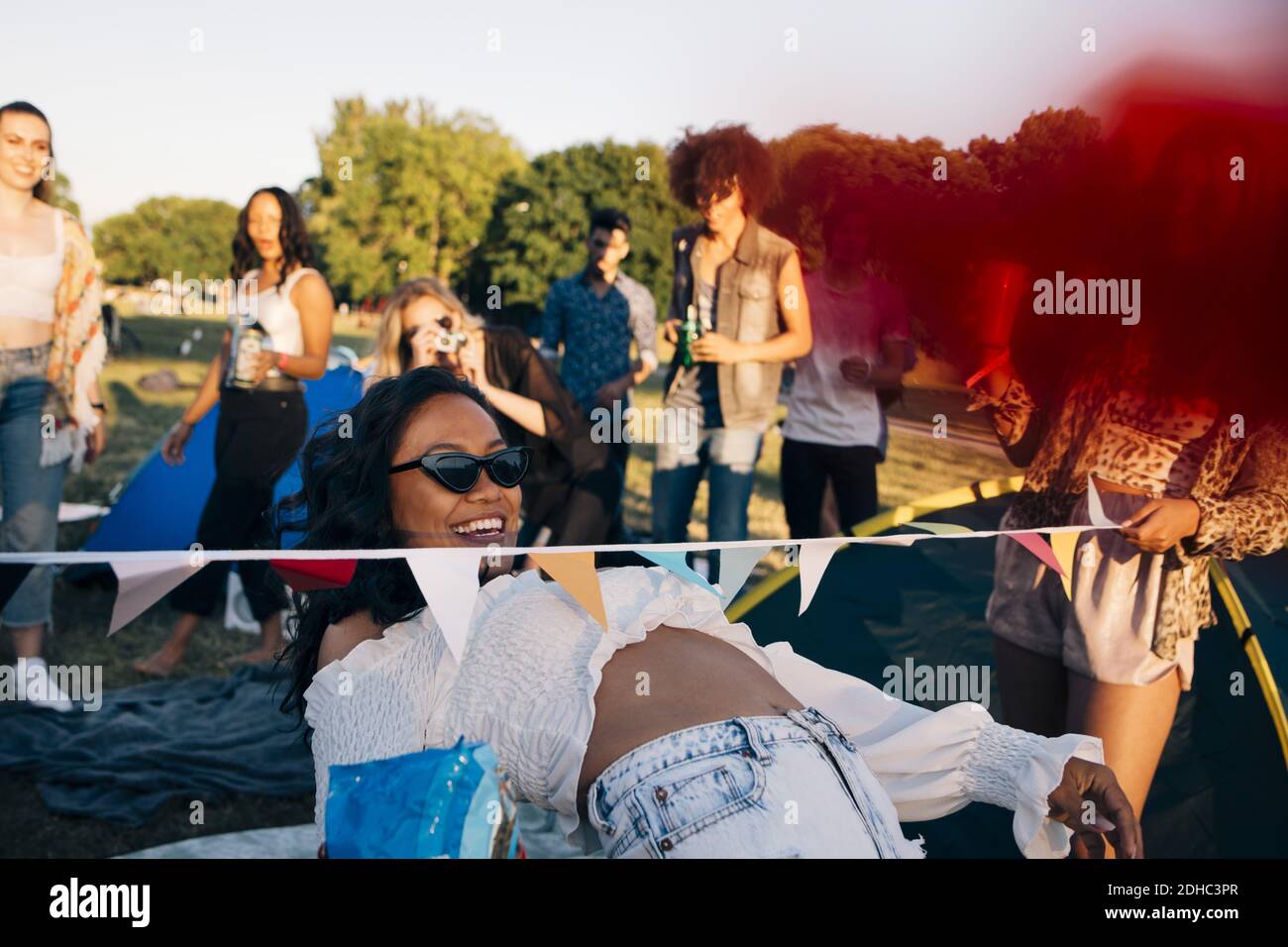 Lächelnde Frau, die Limbo Tanz beim Genießen mit Freunden an Musikfestival Stockfoto