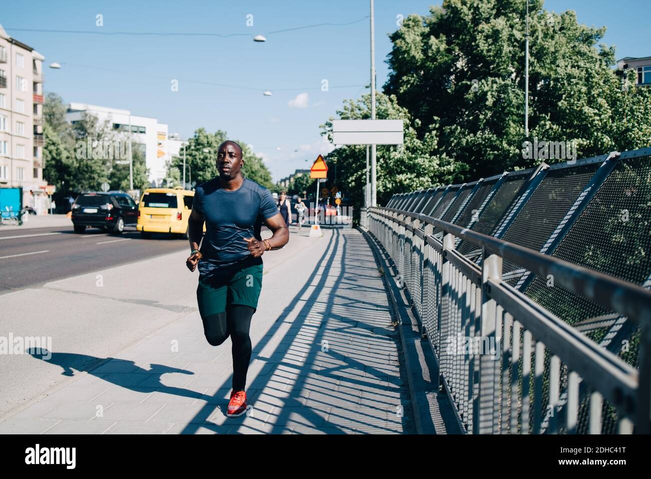 Die ganze Länge des männlichen Athleten Joggen auf dem Bürgersteig an der Brücke In der Stadt Stockfoto