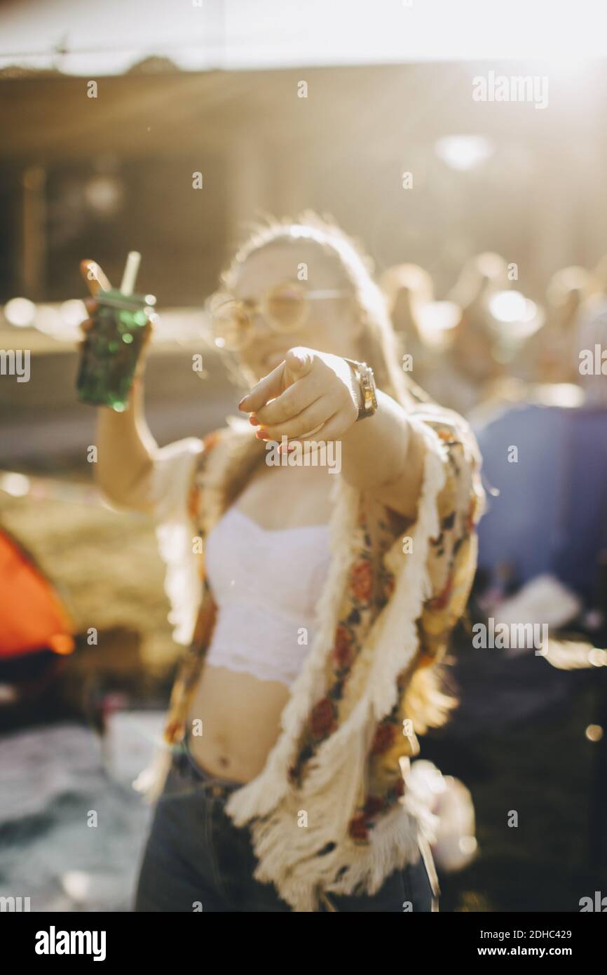 Junge Frau mit Getränk zeigt, während Spaß an der Musik Ereignis Stockfoto