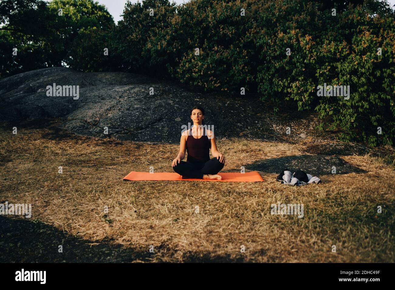 Die ganze Länge der jungen Frau, die Yoga auf Feld in parken Stockfoto