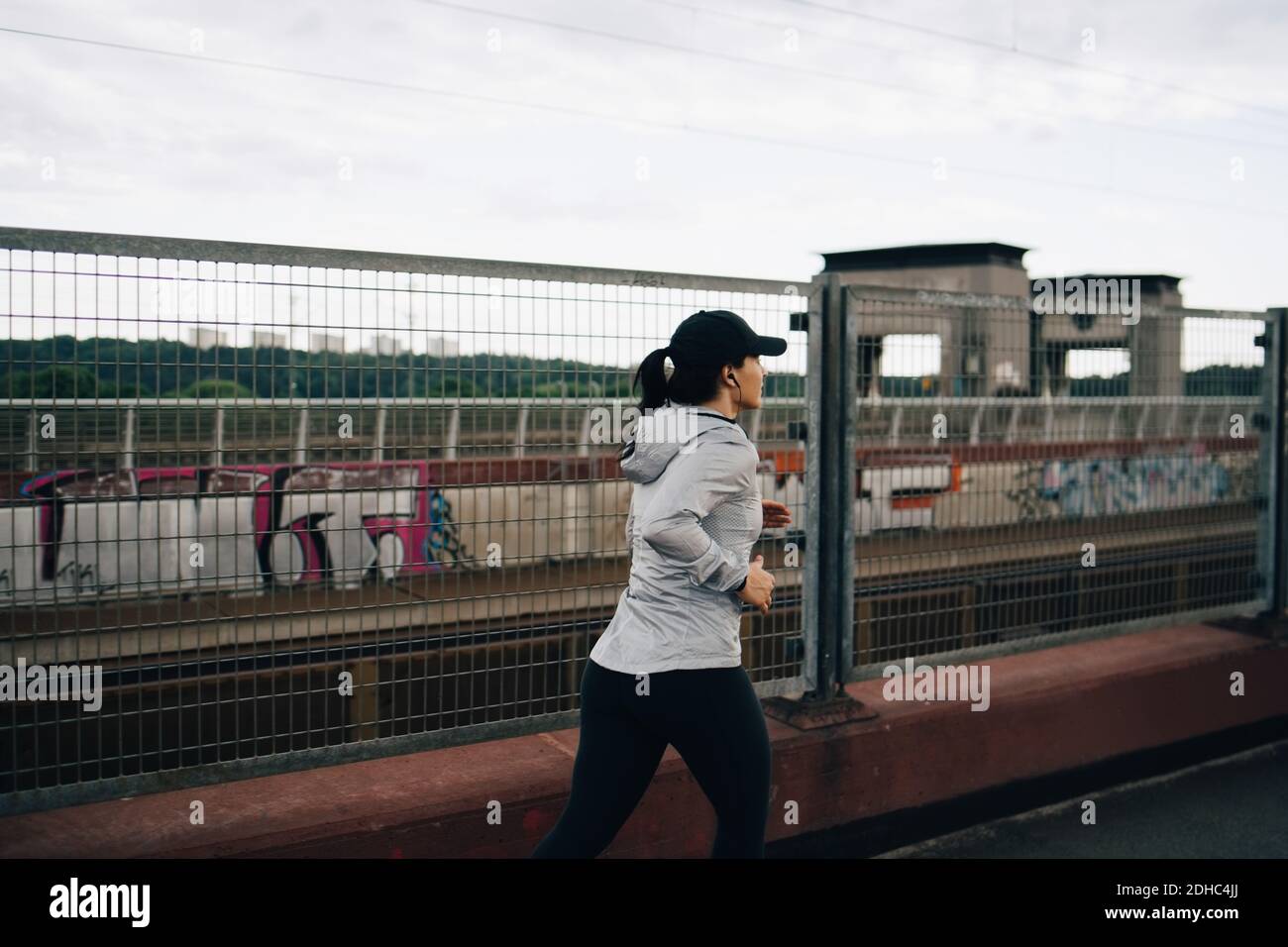 Junge Sportlerin beim Joggen am Zaun auf der Brücke in der Stadt Stockfoto