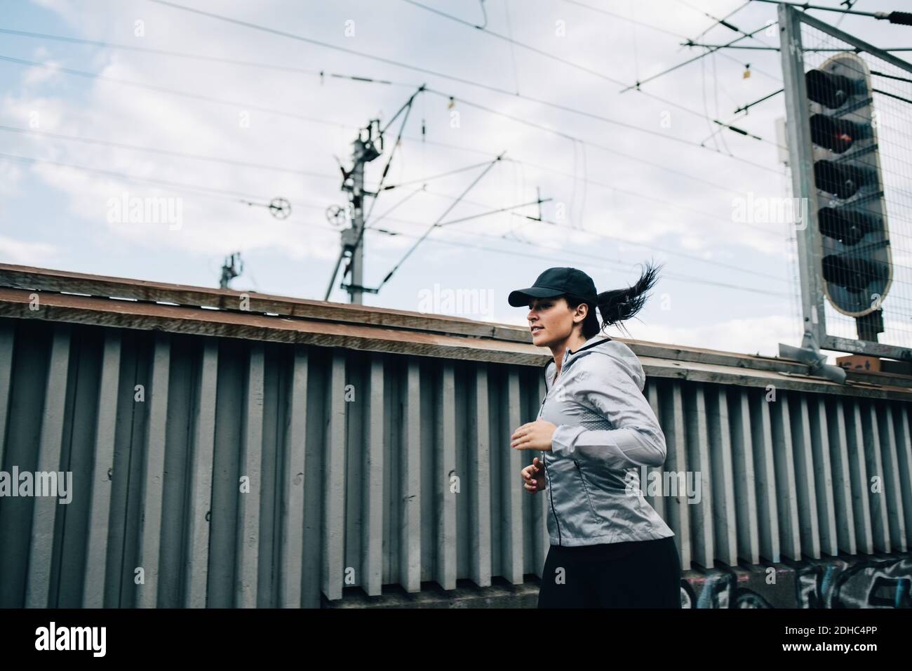 Junge Sportlerin beim Joggen am Zaun auf Fußgängerbrücke in der Stadt Stockfoto