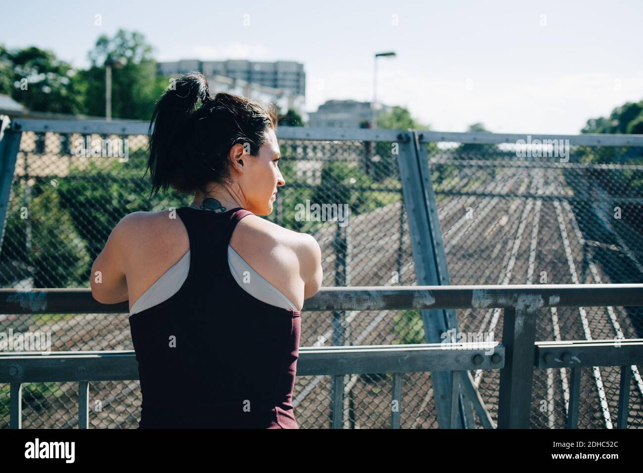 Rückansicht der erschöpften Sportlerin, die sich an der Brücke auf Geländer stützt Stockfoto