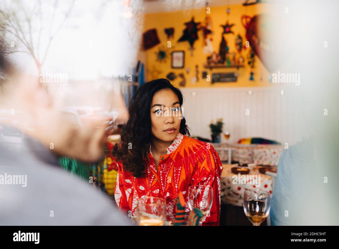 Junge Frau, die von Frau sitzt, während sie einen männlichen Freund anschaut Im Restaurant durch Glasfenster gesehen Stockfoto