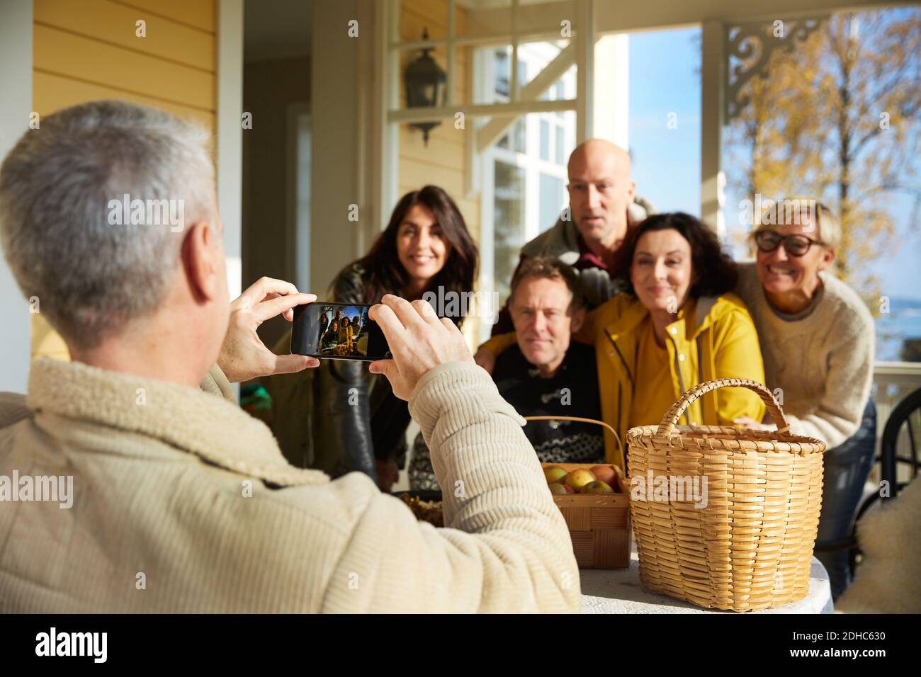 Reifer Mann fotografiert Freunde mit Smartphone auf der Veranda Stockfoto