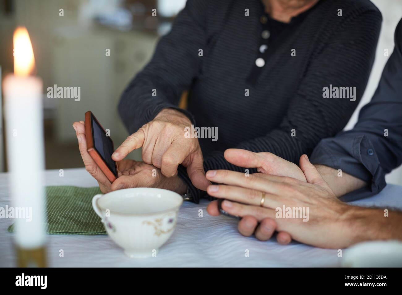 Mittelteil der reifen Mann zeigt auf Smartphone zu Freund Auf dem Tisch Stockfoto