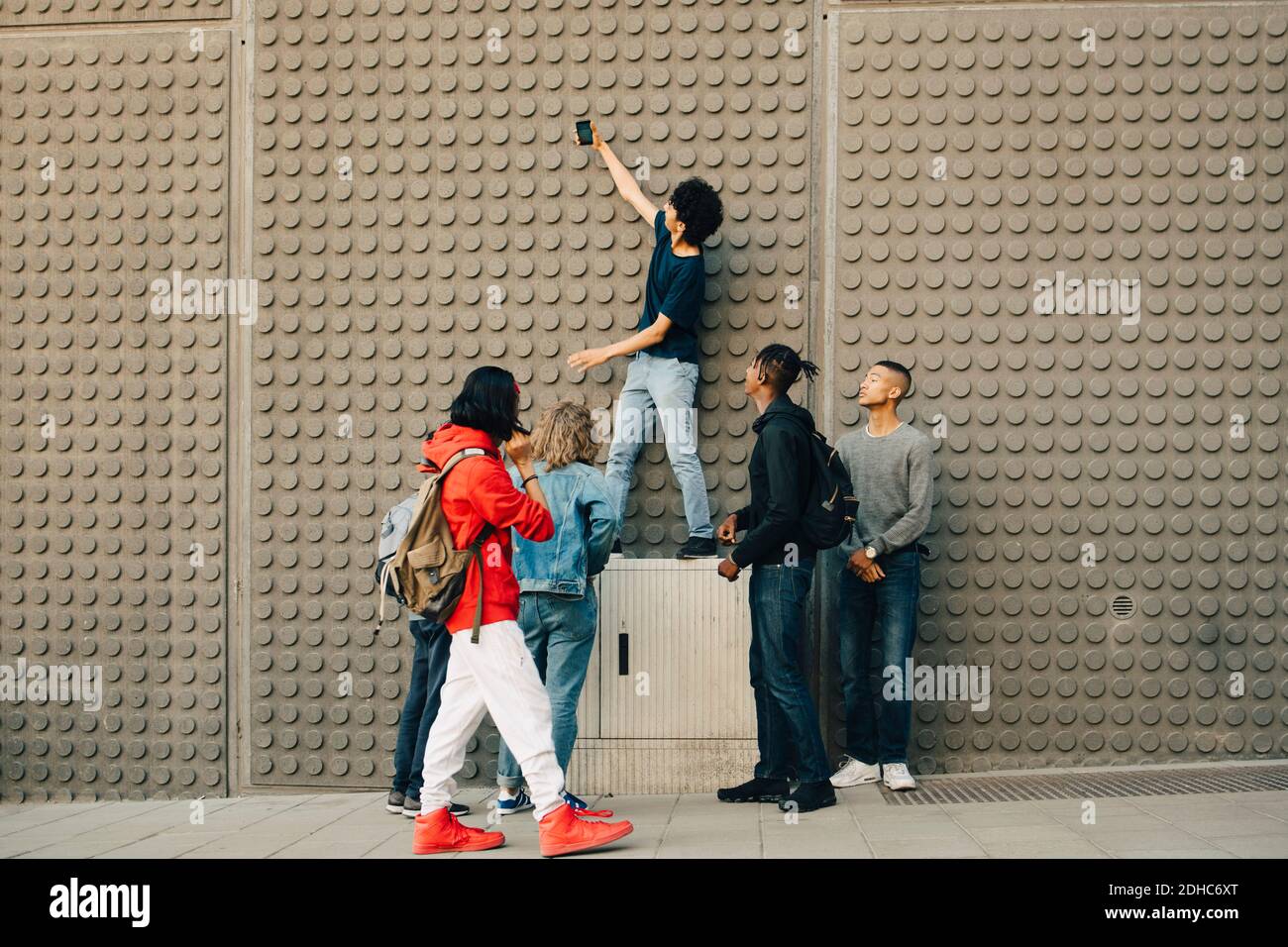 Volle Länge der männlichen Freunde, die Selfie mit Handy Beim Stehen an der Wand in der Stadt Stockfoto